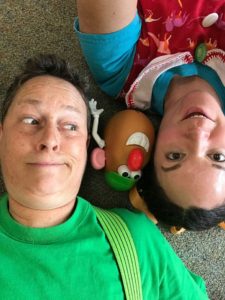 two people lying on the ground with a Mx. Potato Head toy